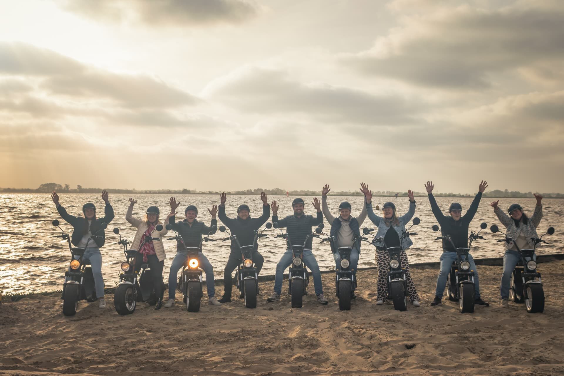 Groep e-chopper rijders op het strand van het Schildmeer bij zonsondergang