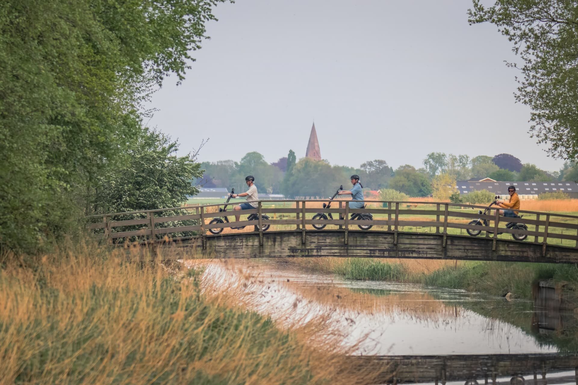 E-choppers rijden over een houten bruggetje bij het Schildmeer